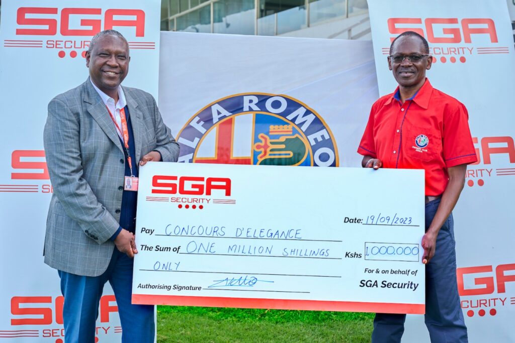SGA Security Kenya Country Manager, Lucas Ndolo hands over a KES 1 Million cheque to Alfa Romeo Owners Club Chairman Peter Wanday as sponsorship for the 51st Concours d'Elegance that will be held on 24th September at the Nairobi Racecourse. SGA Kenya is this year's official security partner where they will provide guarding services, sniffer dogs, walk throughs search and crowd control management. PHOTO/COURTESY 