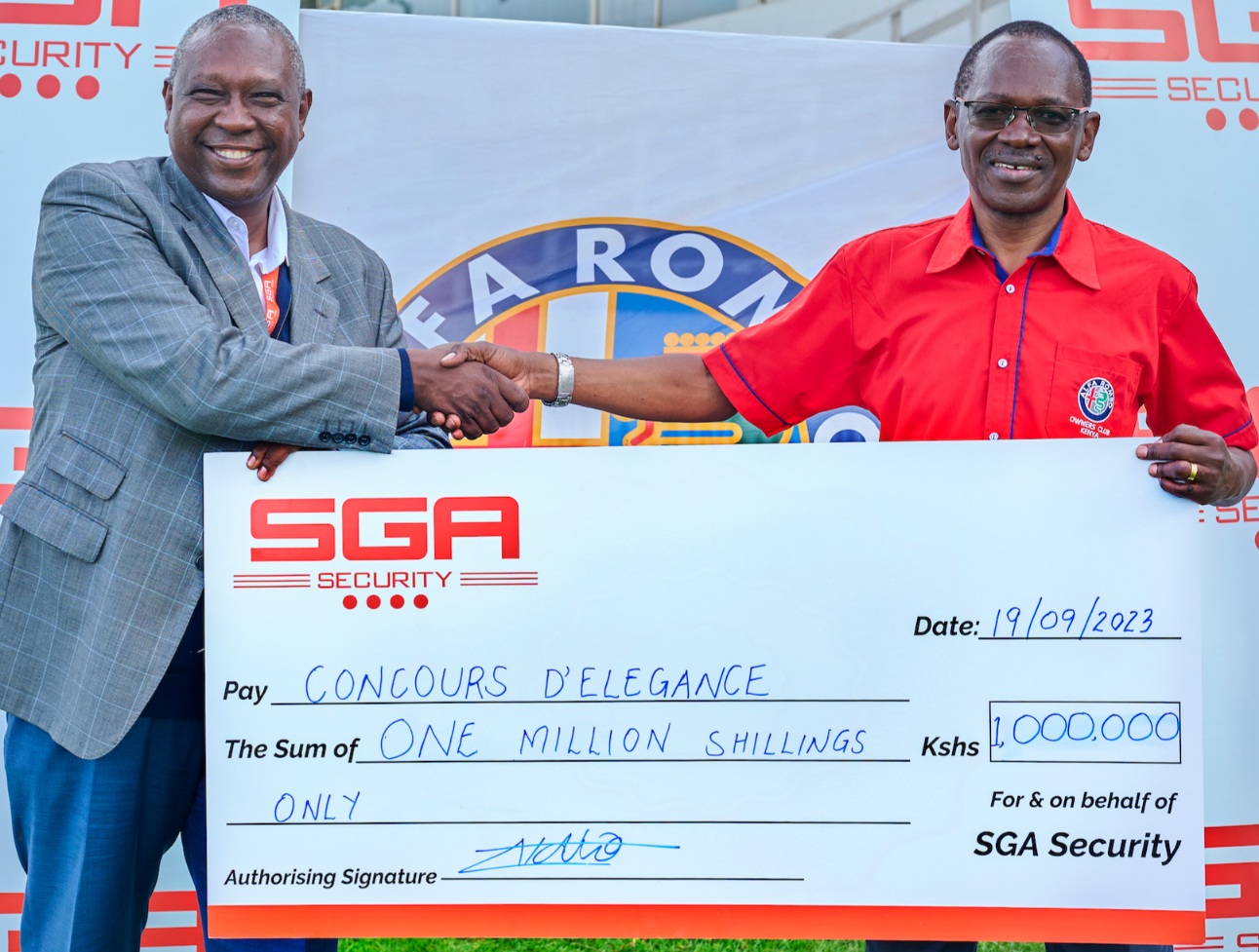 SGA Security Kenya Country Manager, Lucas Ndolo hands over a KES 1 Million cheque to Alfa Romeo Owners Club Chairman Peter Wanday as sponsorship for the 51st Concours d'Elegance that will be held on 24th September at the Nairobi Racecourse. SGA Kenya is this year's official security partner where they will provide guarding services, sniffer dogs, walk throughs search and crowd control management. PHOTO/COURTESY