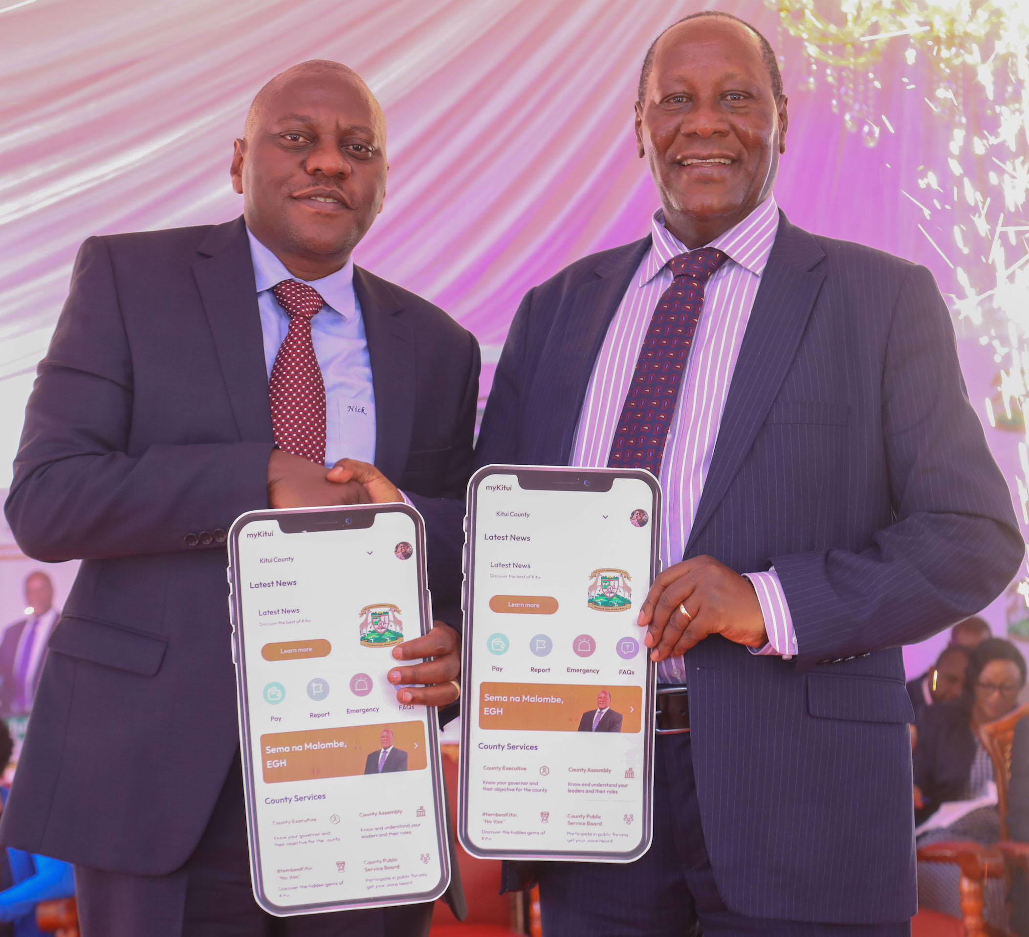 From Left, Safaricom PLC Chief Corporate Security Officer Nicholas Mulila and the Governor of Kitui County H.E Dr. Julius Malombe hold a dummy phone app of the new myKituiCounty App launched at the county headquarters in Kitui County. Kitui county becomes the second county in the Eastern Region to launch the digitisation of its services through the MyCounty app. The app will help the county manage their revenue and reach out to most of its residents. PHOTO/COURTESY.